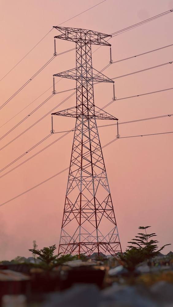 A high-voltage transmission tower at dusk in Abuja, Nigeria